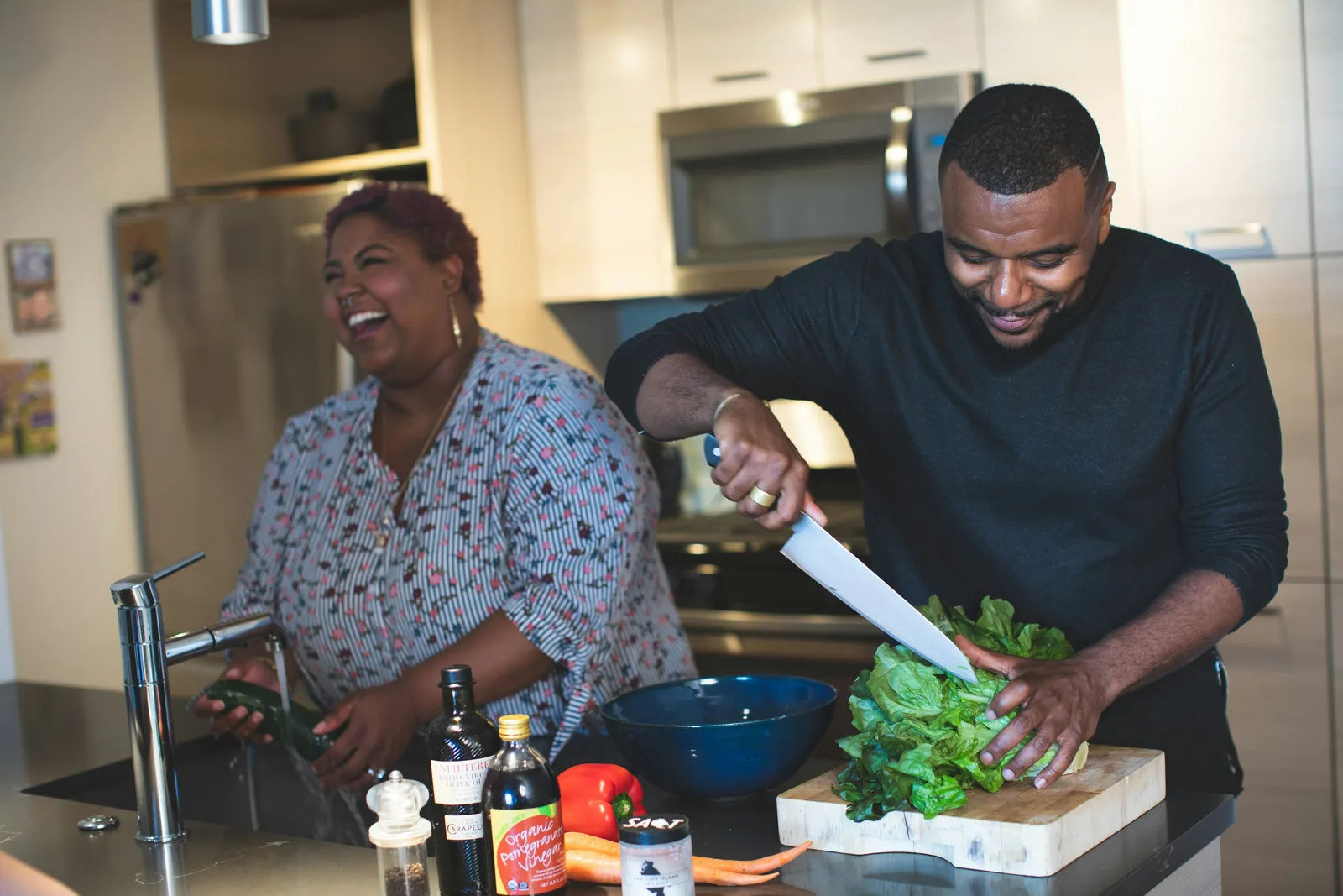 Two people preparing a salad together in a home kitchen