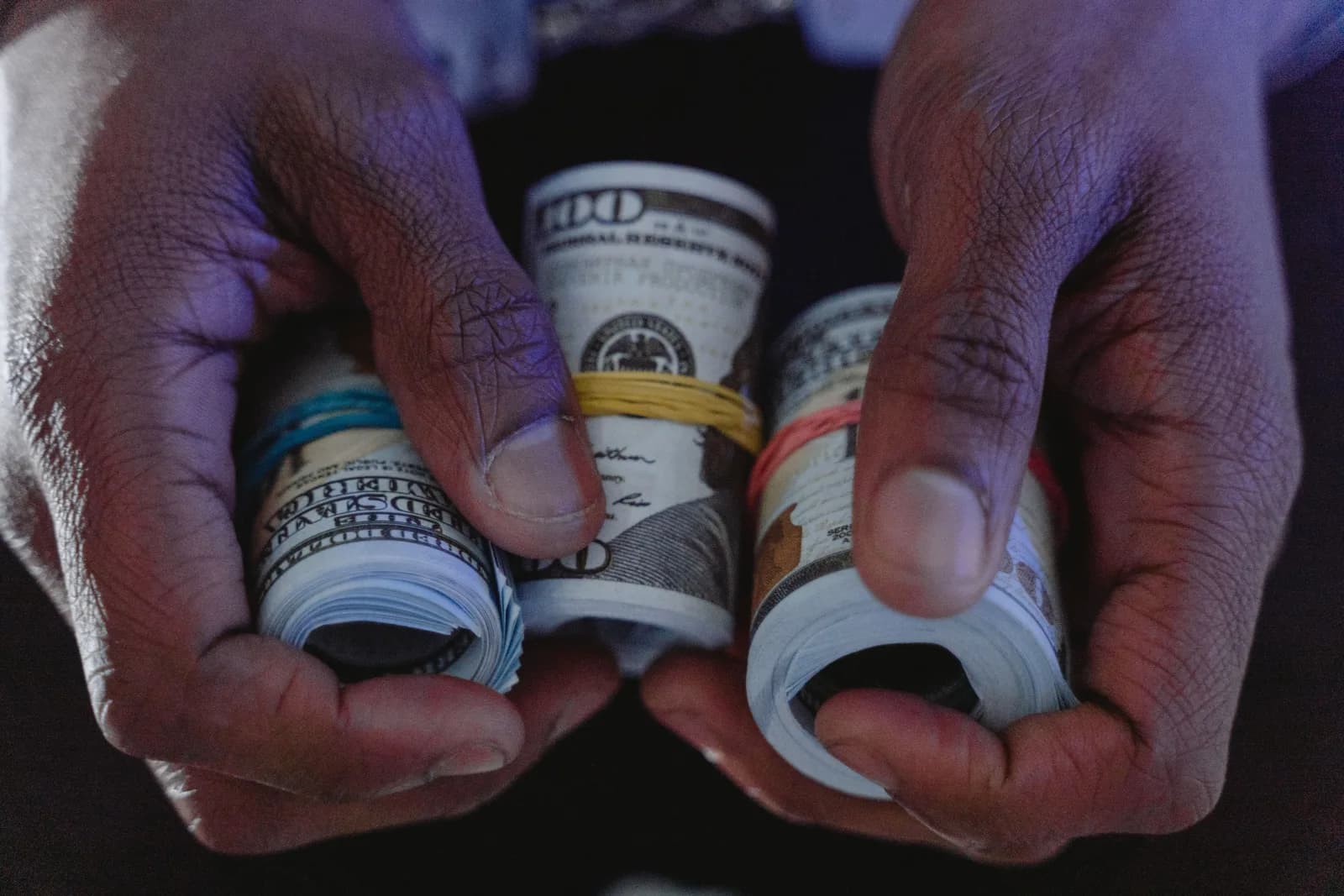 Hands holding several rolls of United States currency