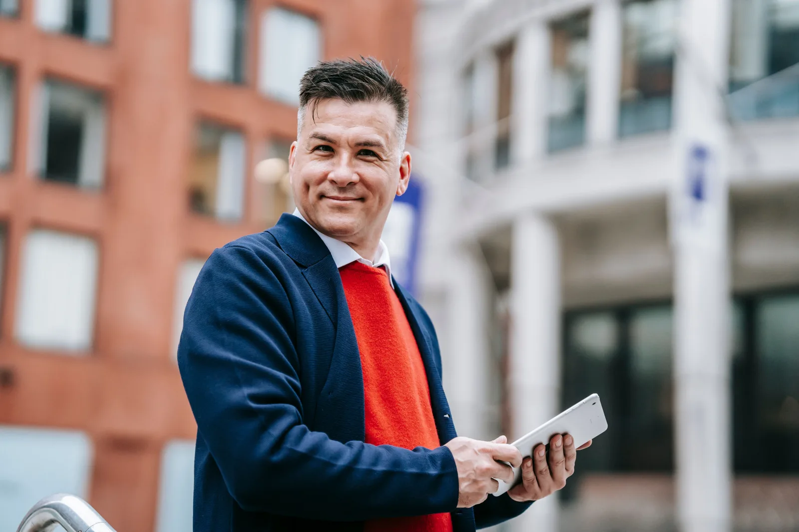 Adult man standing outdoors and holding a tablet